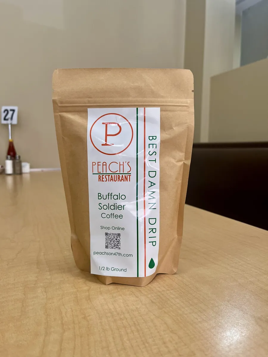 A kraft bag of Peach’s Buffalo Soldier coffee labelled “Best Damn Drip” on a restaurant table