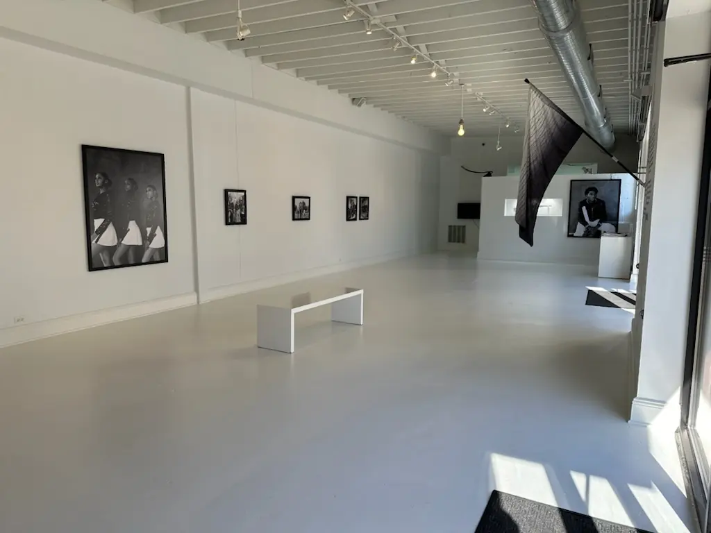 A freestanding white wall displaying a large black-and-white portrait and a recessed vitrine.