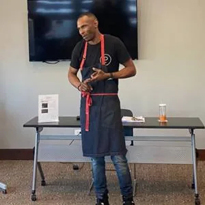 Executive Chef Trillis Rollins in an apron, leading a cooking demonstration