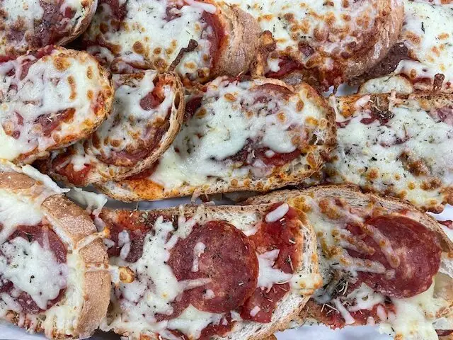 Trays of toasted bread topped with melted cheese and pepperoni