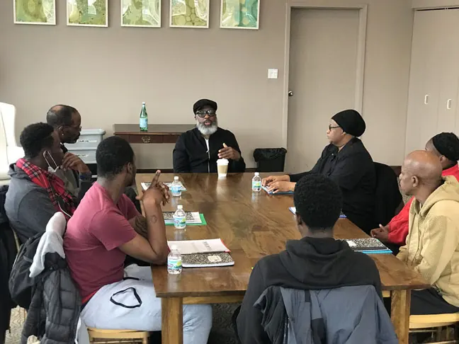 Young adults seated around a wooden table in a session with an instructor