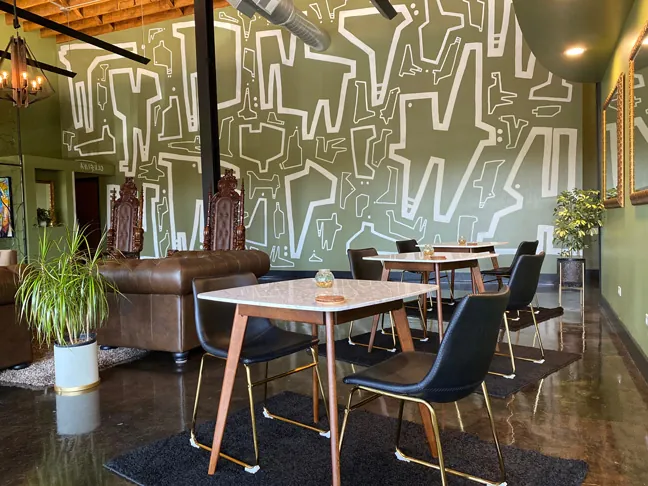 Bronze: a white table and black chairs in front of a bold green-and-white mural wall
