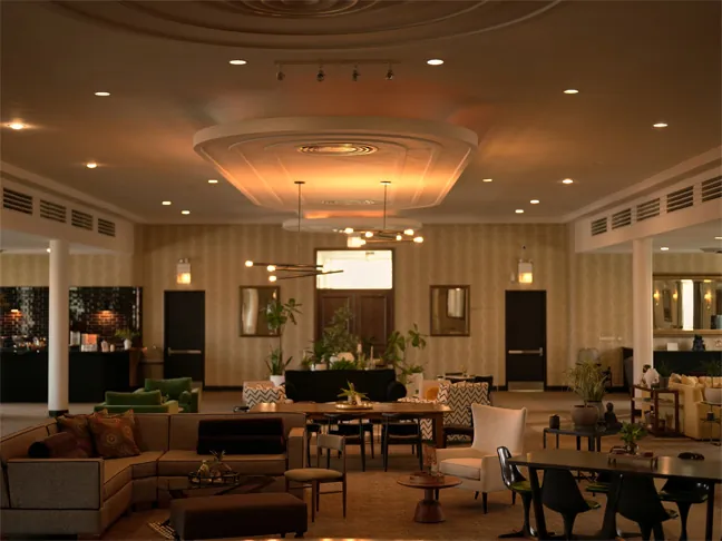 The Parlor Room: lounge sofas, communal tables and greenery under a domed, softly lit ceiling