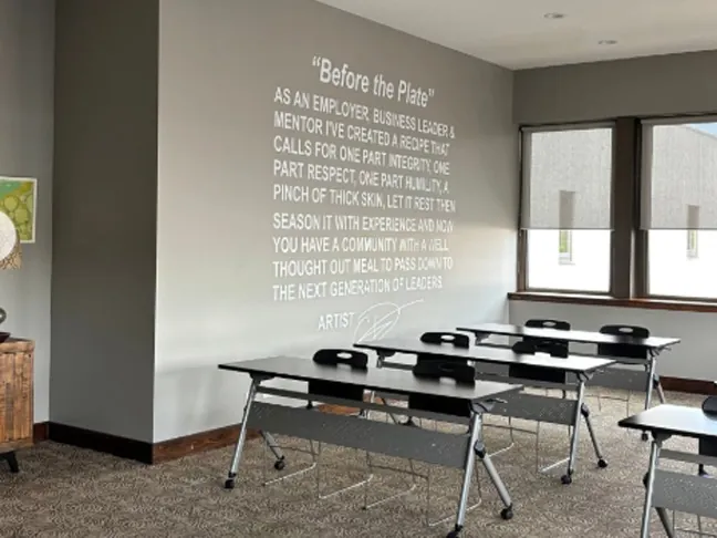 The Training Room: rows of training tables facing a wall printed with a quote titled Before the Plate