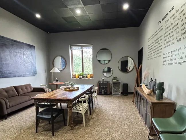 The Writer’s Room: a long conference table with eight chairs, round mirrors and a lounge sofa